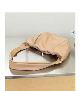 Vista detallada que muestra la textura del bolso dumpling plisado en cuero PU suave beige