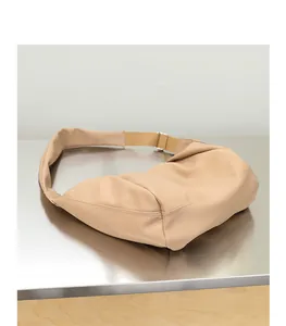 Detalle de cerca del bolso de cuero PU beige plisado sobre superficie metálica