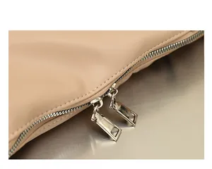 Primer plano de cremalleras metálicas dobles en un bolso beige de cuero sintético suave