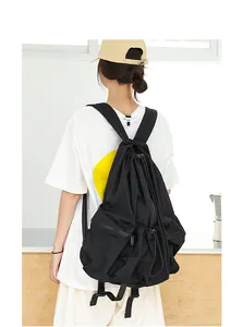 Vista trasera de una modelo con una mochila de nailon negro plisada con cordón ajustable