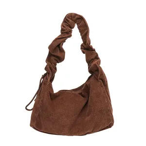 Retro brown corduroy shoulder bag with elegant ruffled strap and minimalist design.