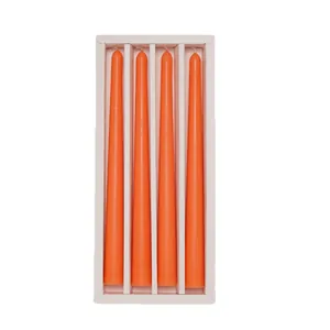 Set of four vibrant orange taper candles arranged in a minimalist white gift box display.
