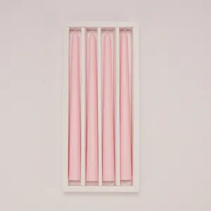 Detailed view of four pink taper candles neatly arranged in a minimalist white box