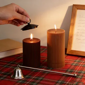 Detail view of fluted pillar candles being extinguished with a metal snuffer set.