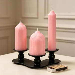Set of pink ribbed geometric pillar candles on a sleek black candle holder with matches.