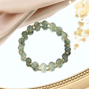 Macro detail of green rutilated quartz beads bracelet with golden accents on a mirror
