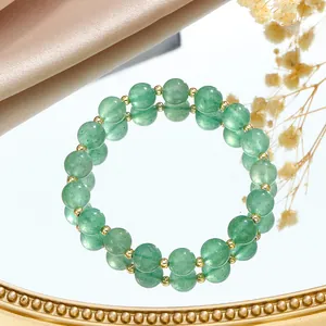 Elegant close-up of green crystal bead bracelet with gold spacers on a reflective mirror