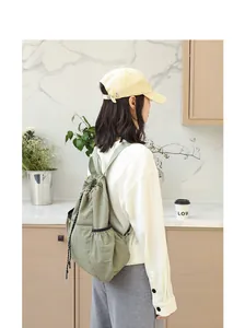 Lifestyle-Ansicht einer Frau mit einem grünen Nylon-Rucksack mit Kordelzug in Küche.
