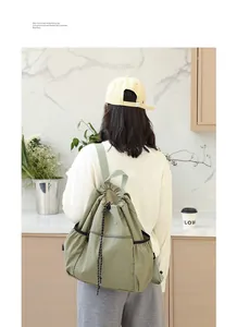 Rückansicht einer Frau mit einem grünen Kordelzug-Rucksack aus Nylon in einer Küche