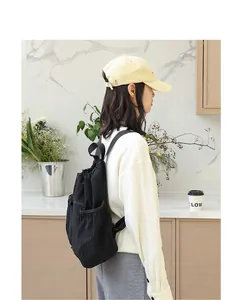 Seitenansicht eines lässigen schwarzen Nylon-Rucksacks mit Kordelzug, getragen von einem Model.