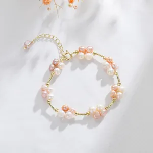 Elegant freshwater pearl floral bracelet with gold-tone links on white linen backdrop.