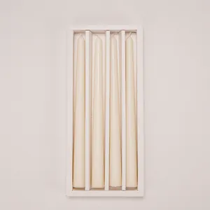 Detail view of four cream-colored long tapered candles in a white gift packaging box