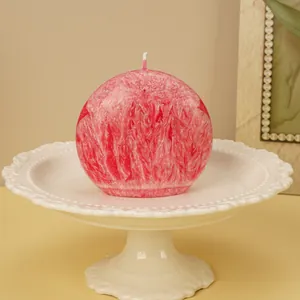 Macro close-up of a pink round textured candle displayed on a white ceramic pedestal plate