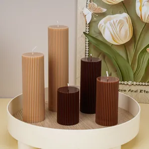 Close-up detail of elegant ribbed pillar candles in chocolate and tan shades on a wood tray.