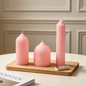 Elegant trio of pink ribbed pillar candles in varied heights displayed on a rustic wooden board.