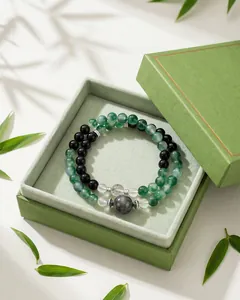 Detailopname van groene chalcedoon en obsidiaan kralenarmband in een groene geschenkverpakking