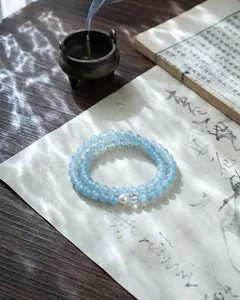 Macro view of blue chalcedony beaded bracelet featuring a white pearl on vintage paper