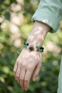 Macrodetail van armbanden van mosagaat en obsidiaan gedragen om een pols.