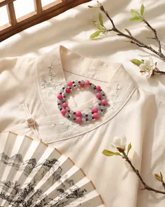 Detailansicht eines rosa-blauen Granat-Chalcedon-Perlenarmbands auf Hanfu-Kleidung.