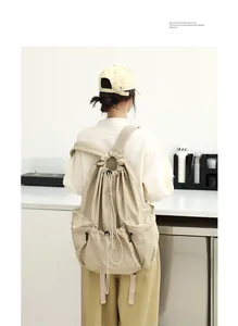 Detalle de mochila de nailon beige plisada con cordón usada por una modelo en un café