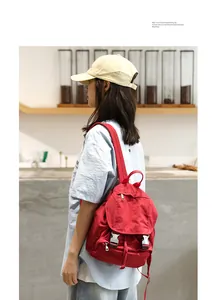 Vista de detalle de mochila de lona lavada roja llevada por una modelo en un café moderno