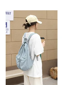 Lifestyle-Ansicht eines hellblauen Nylon-Rucksacks mit Kordelzug und Faltenfach.