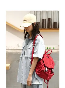Mochila vintage de lona roja llevada por una modelo en una cafetería de estilo casual.