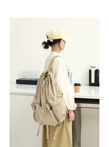 Vista lateral de una mochila grande de nailon beige con cordón y detalles plisados
