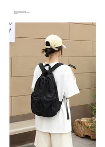 Rückansicht eines Models mit einem schwarzen, gefalteten Nylon-Rucksack mit Kordelzug.