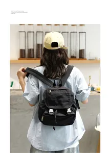 Vista posterior de una modelo con una mochila de lona lavada negra en una cafetería