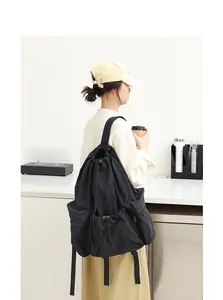 Vista trasera de una mochila grande de nailon negro con cordón ajustable y pliegues.