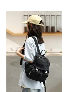 Vista lateral de una modelo con una mochila de lona negra lavada de estilo retro