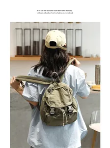 Vista detallada de una mochila retro de lona lavada verde oliva llevada por una modelo