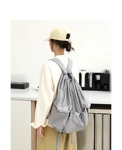 Mochila de nailon gris con cordón llevada por una modelo en una cafetería