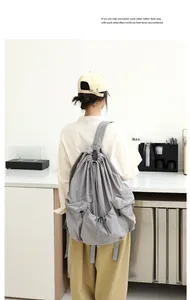 Mochila grande de nailon gris con cordón y diseño plisado usada por una modelo