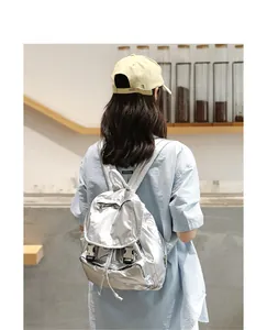 Vista detallada de una mochila vintage plateada metalizada usada por una modelo