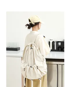 Vista trasera de modelo con elegante mochila de nailon plisada en color crema