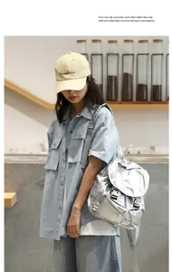 Vista lifestyle de una mochila plateada metalizada llevada por una modelo en una cafetería