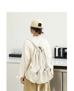 Vista posterior de modelo con una elegante mochila de nailon beige con cordón ajustable