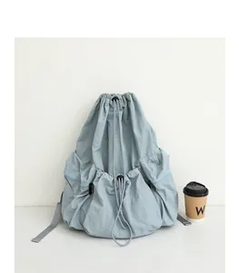 Vista detallada de una mochila de nailon azul claro con cordón y diseño plisado.