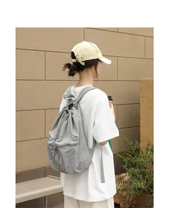 Rückansicht eines grauen Nylon-Rucksacks mit Kordelzug, von einem Model getragen