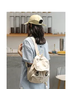 Vista trasera de una mujer con mochila vintage de lona beige en una cafetería acogedora.