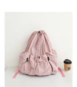 Detalle de la mochila de nailon rosa plisada con cordón en un entorno minimalista