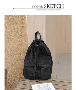 Nahaufnahme eines schwarzen, gefalteten Nylon-Rucksacks mit Kordelzug auf einem Holztisch.