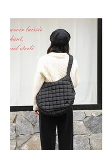 Stylish black quilted nylon shoulder bag worn over a white knitted sweater in detail view