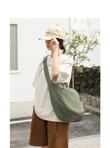 Modelo femenina con un bolso bandolera de lona a cuadros verdes en un entorno urbano