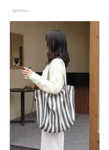 Vista lifestyle di una donna con una grande borsa tote in tela a righe in un caffè