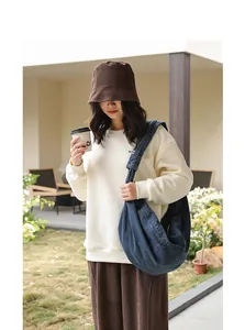 Large casual blue denim dumpling bag with a unique knotted strap shown on a female model.