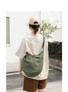 Modelo femenina con bolso de lona a cuadros verdes en un entorno informal al aire libre