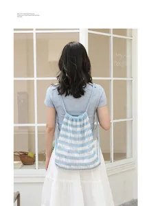 Vista trasera de una mujer con una mochila de punto a rayas azules y blancas con cordón ajustable